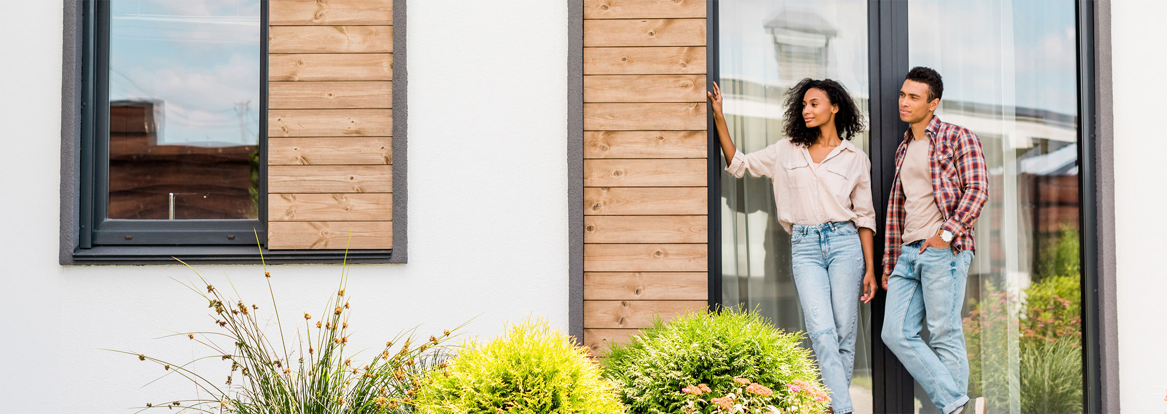 Mies ja nainen seisomassa talonsa ovella tyytyväisinä
